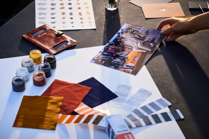 Mesa de diseño McLaren con telas, pinturas, muestras de color y foto histórica de piloto.