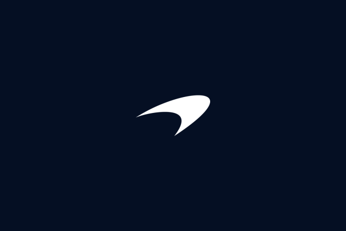 Icono Speedmark de McLaren blanco sobre fondo azul noche, símbolo de velocidad y herencia.