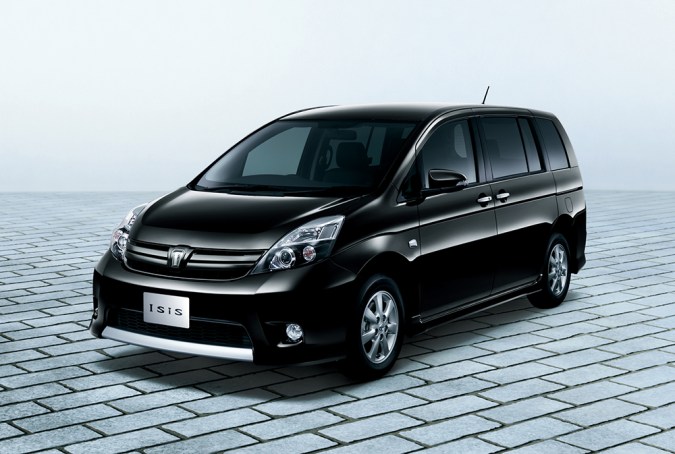 Toyota Isis negro, monovolumen japonés, fotografiado en un estudio sobre una superficie pavimentada.