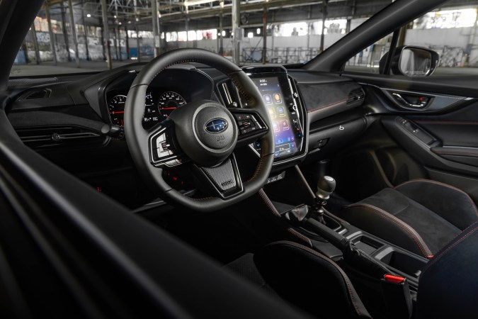 Interior del Subaru con volante, pantalla vertical táctil, palanca manual y asientos deportivos negros.