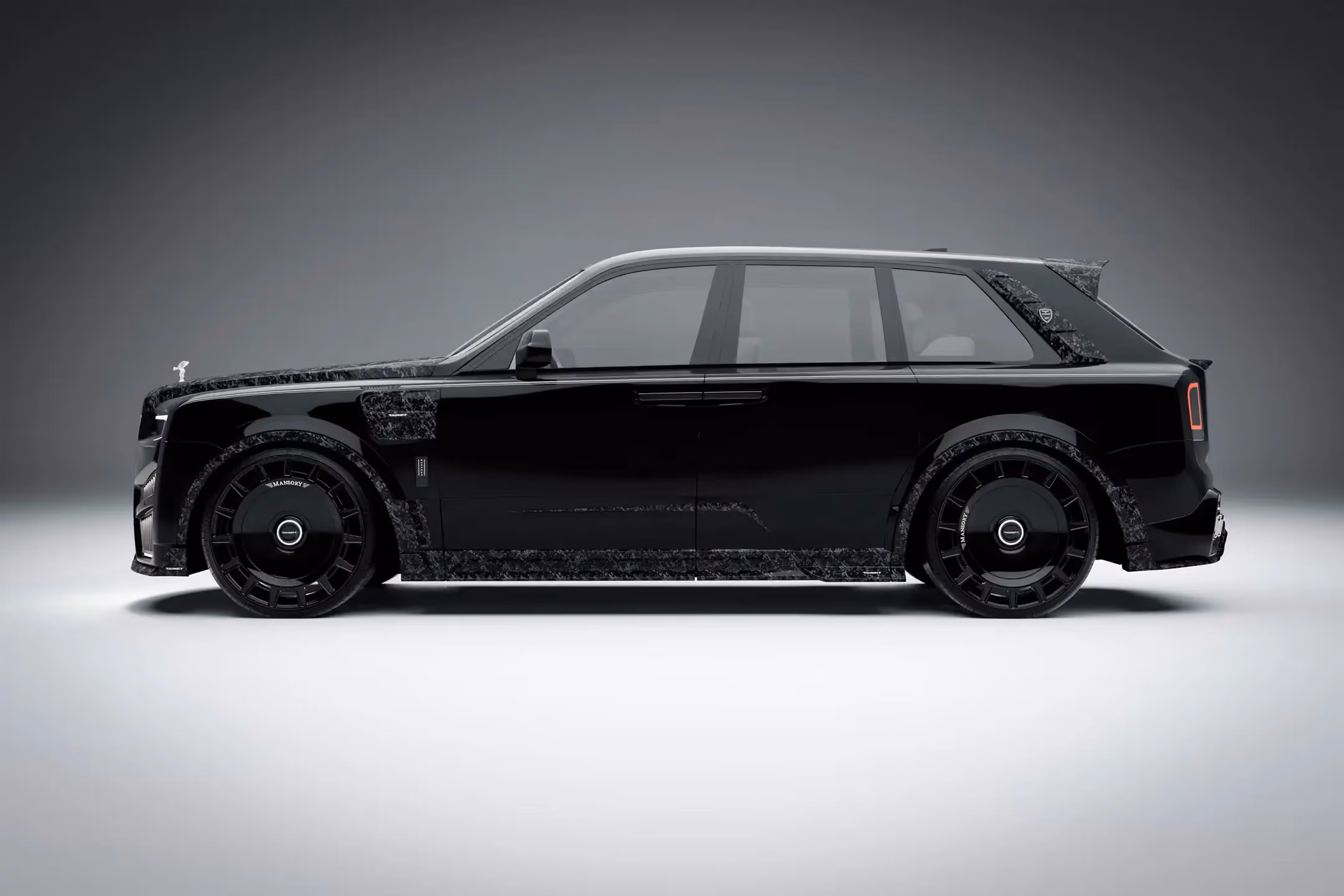Rolls-Royce Cullinan Mansory negro visto de perfil, con carrocería personalizada y llantas aerodinámicas de lujo.