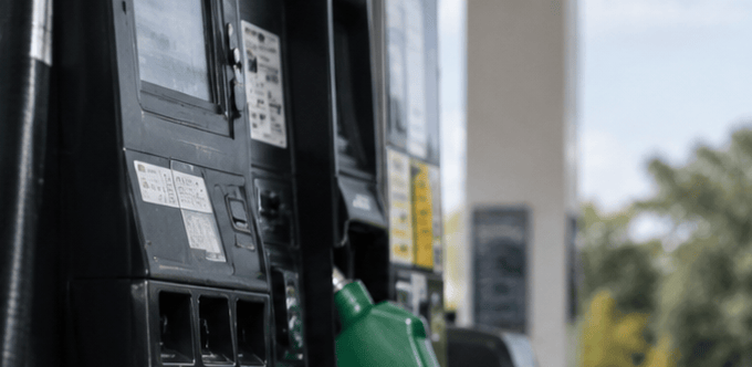 Camioneta gris carga etanol E85 con surtidor verde en estación de servicio al aire libre.