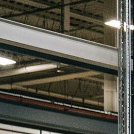 Trabajadores con cascos de EE.UU. ensamblan SUV eléctrico blanco en fábrica moderna con robots industriales.