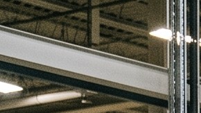 Trabajadores con cascos de EE.UU. ensamblan SUV eléctrico blanco en fábrica moderna con robots industriales.
