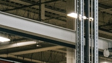 Trabajadores con cascos de EE.UU. ensamblan SUV eléctrico blanco en fábrica moderna con robots industriales.