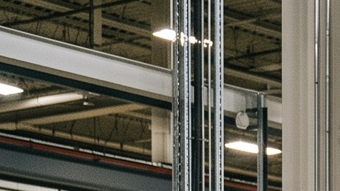 Trabajadores con cascos de EE.UU. ensamblan SUV eléctrico blanco en fábrica moderna con robots industriales.