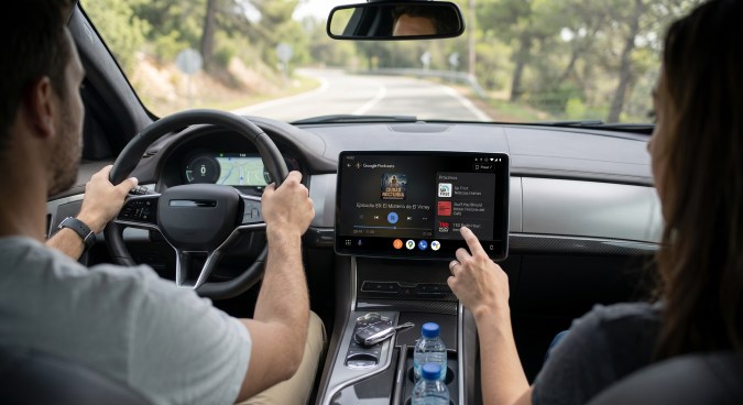 Conductor y pasajera utilizan Google Podcasts en Android Auto durante un viaje por carretera.