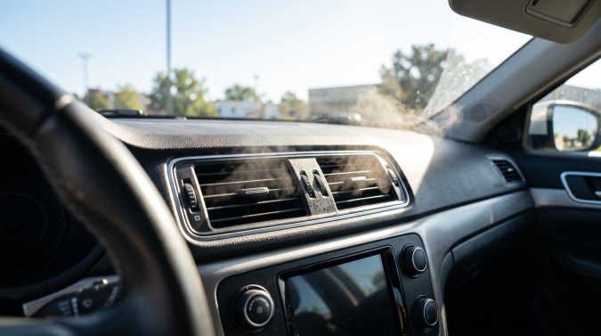 Humo blanco saliendo de las rejillas del aire acondicionado en el interior de un automóvil.