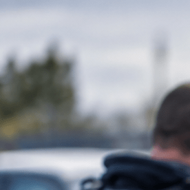 Agente de ICE detiene a hombre esposado junto a SUV negro con apoyo del FBI.