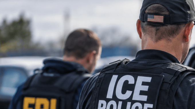 Agente de ICE detiene a hombre esposado junto a SUV negro con apoyo del FBI.