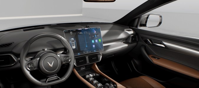 Interior moderno del VinFast VF8 con pantalla táctil grande, volante y asientos de cuero beige.
