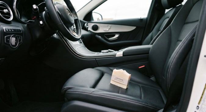 Jabón en barra de lavanda colocado sobre el asiento del piloto de un auto de lujo con interior de cuero negro.