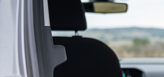 Un conductor sacando una rueda de repuesto del maletero de un coche gris en una carretera