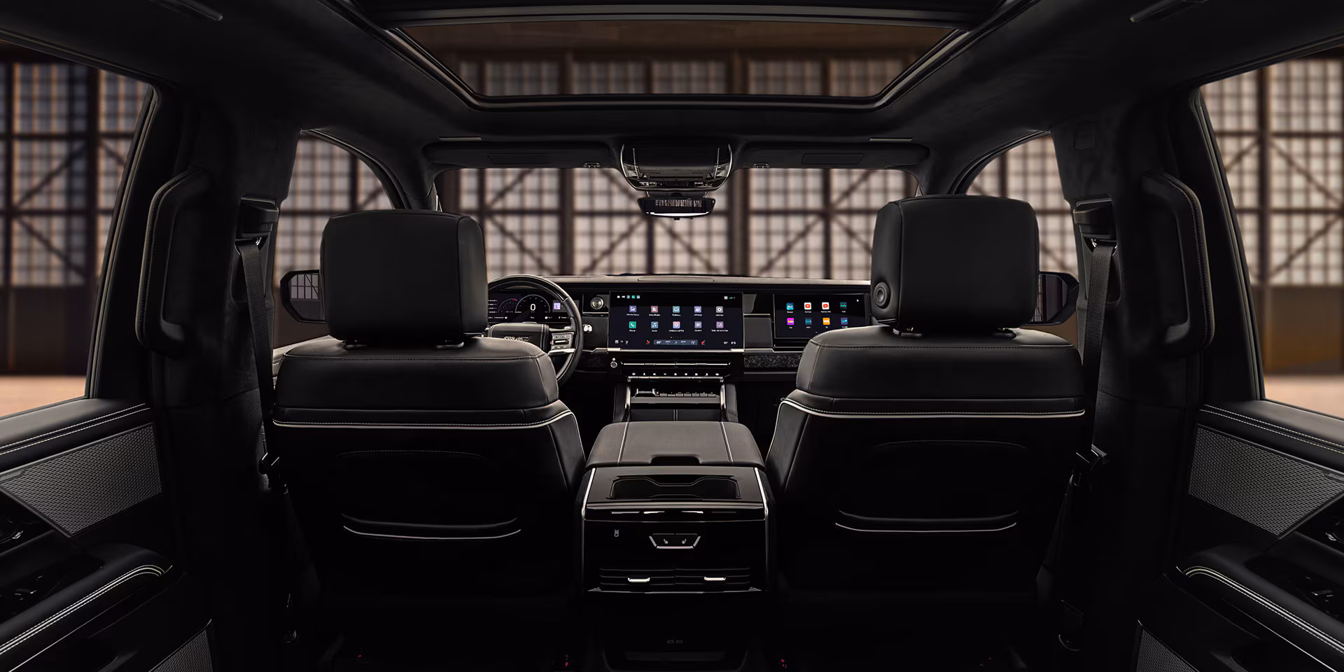 Lujoso diseño interior de la GMC Sierra 1500 mostrando asientos de cuero negro, tablero con amplias pantallas digitales y techo panorámico.