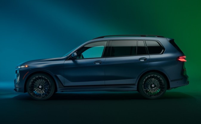 Perfil lateral de un SUV BMW ALPINA XB7 azul oscuro con rines grandes en un estudio