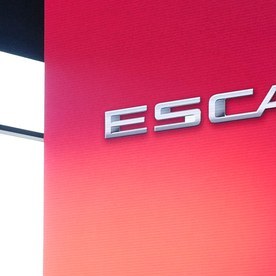 SUV eléctrico Cadillac Escalade IQ blanco sobre un escenario con luces rojas y turquesa