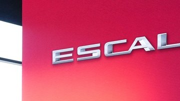 SUV eléctrico Cadillac Escalade IQ blanco sobre un escenario con luces rojas y turquesa