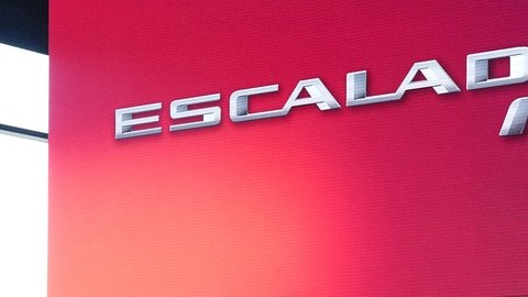 SUV eléctrico Cadillac Escalade IQ blanco sobre un escenario con luces rojas y turquesa