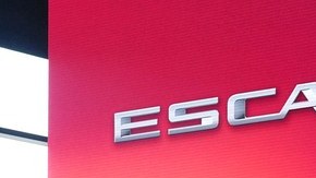 SUV eléctrico Cadillac Escalade IQ blanco sobre un escenario con luces rojas y turquesa