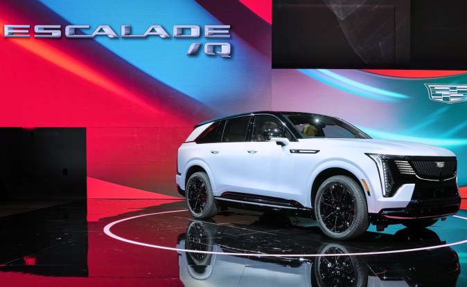 Cadillac Escalade IQ blanco con faros verticales visto de lado en un escenario de presentación
