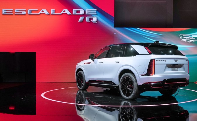 Parte trasera de un Cadillac Escalade IQ blanco con calaveras verticales sobre un escenario rojo