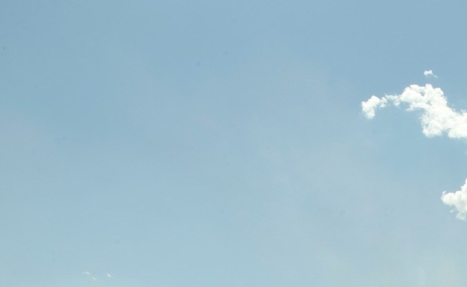 Cosechadora descargando trigo en un camión de grano en medio de un campo dorado bajo un cielo azul con nubes