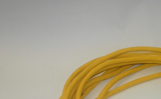Extensión eléctrica amarilla enrollada con clavija de tres patas y un extremo con tres tomacorrientes