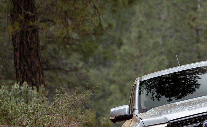 Ford Ranger plateada bajando por un sendero de tierra entre pinos, vista de frente.