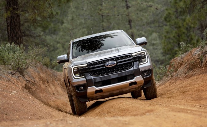 Ford Ranger plateada bajando por un sendero de tierra entre pinos, vista de frente.