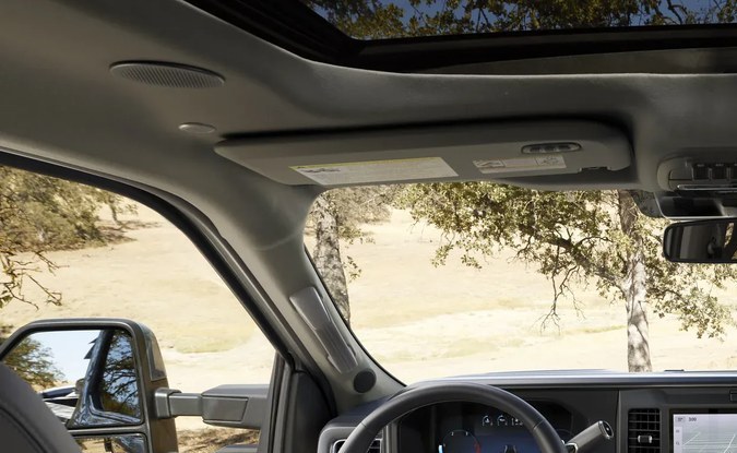 Cabina de una pickup Ford Super Duty con volante, pantalla central táctil, techo panorámico y asientos grises.