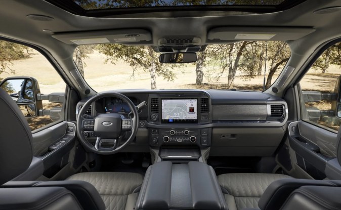 Cabina de una pickup Ford Super Duty con volante, pantalla central táctil, techo panorámico y asientos grises.