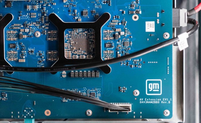 Placa electrónica azul de la computadora central de GM con un procesador y cables conectados.