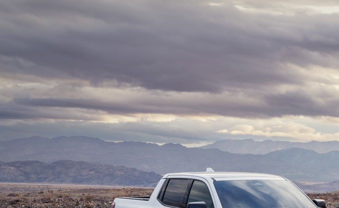 Dos GMC Sierra EV 2026, versiones AT4 blanca y Elevation azul, estacionadas en el desierto