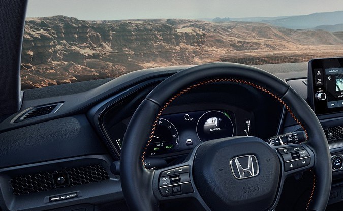 Tablero de la Honda CR-V híbrida con volante de costuras naranjas, pantalla táctil y palanca de cambios.