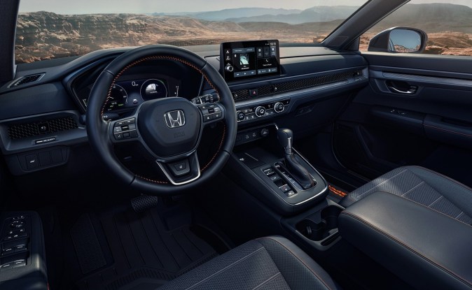 Tablero de la Honda CR-V híbrida con volante de costuras naranjas, pantalla táctil y palanca de cambios.