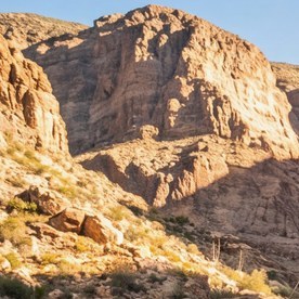 Jeep Gladiator Rubicon con llantas todoterreno grandes avanzando sobre rocas en un cañón desértico.