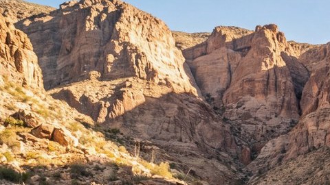 Jeep Gladiator Rubicon con llantas todoterreno grandes avanzando sobre rocas en un cañón desértico.