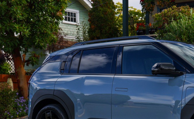 Kia EV3 2027 azul claro estacionado en una calle residencial junto a una casa con jardín