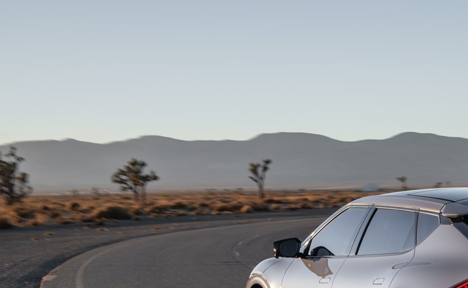 Parte trasera de un Kia EV6 gris tomando una curva en una carretera desértica.