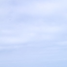 SUV eléctrico Kia EV9 blanco avanza de frente por una carretera junto al mar.