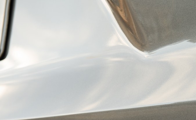 Primer plano del emblema PHEV en la compuerta trasera de una SUV Kia color gris claro.