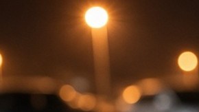 Mano con guante negro intenta abrir la puerta de un sedán gris en un estacionamiento iluminado de noche
