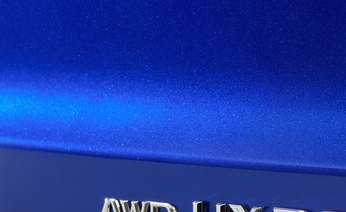 Primer plano del emblema cromado AWD UX300h sobre la carrocería azul del Lexus.