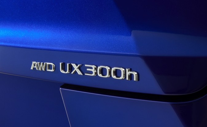 Primer plano del emblema cromado AWD UX300h sobre la carrocería azul del Lexus.