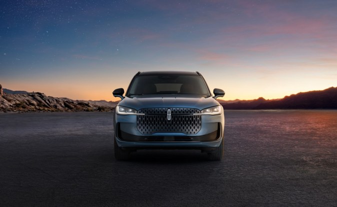 Vista frontal de una SUV Lincoln Corsair gris azulada sobre una explanada al atardecer.
