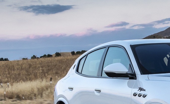 Maserati Grecale Folgore eléctrico blanco circulando al atardecer por una carretera entre colinas