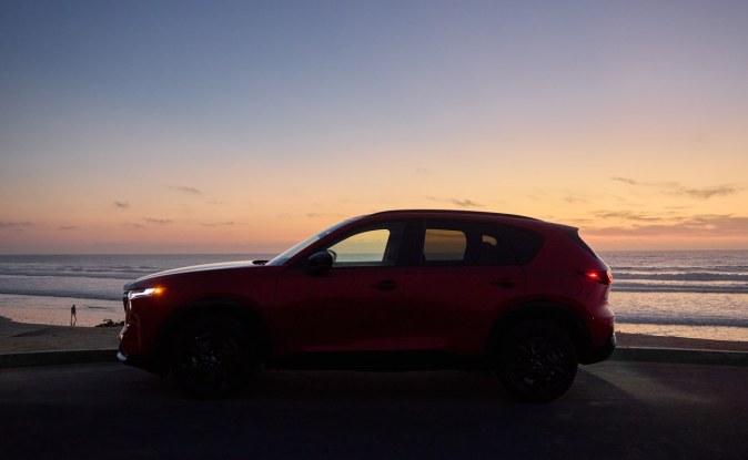 Mazda CX-5 roja vista de lado con el cielo del atardecer de fondo.