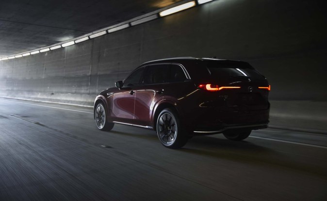 Mazda CX-90 rojo oscuro visto desde atrás con las luces traseras encendidas dentro de un túnel.