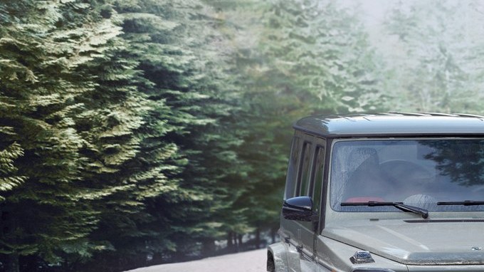 Todoterreno Mercedes-Benz Clase G gris avanzando por un camino nevado entre pinos.