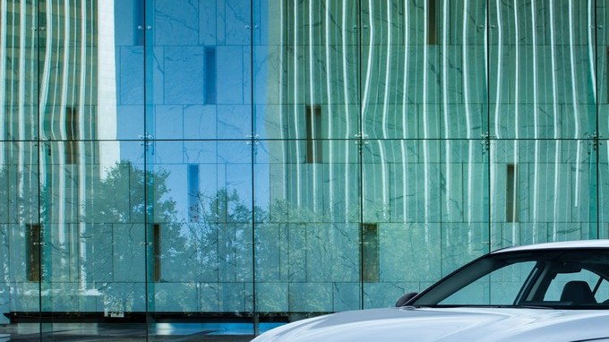 Nissan Altima SR blanco estacionado frente a un edificio moderno de cristal